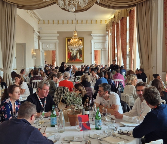 Un dîner élégant dans une salle raffinée où des participants échangent autour d’une table.