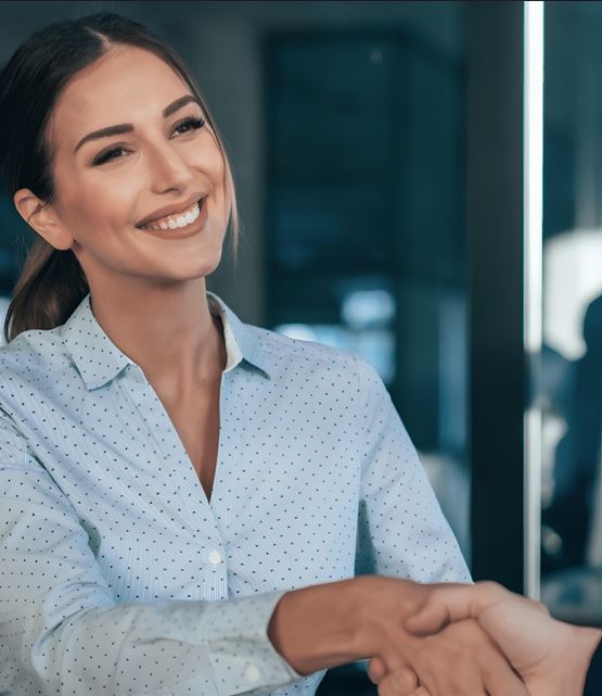 Femme en costume professionnel, souriante, prête à discuter dans un environnement de travail moderne