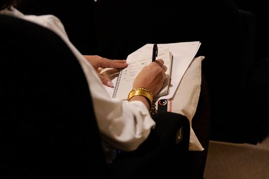 Participant prenant des notes lors d’une conférence aux Rendez-Vous SolutionsCSE, avec carnet et documents posés sur les genoux