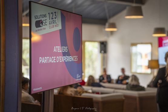 Écran indiquant “Ateliers partage d’expériences” lors des Rendez-Vous SolutionsCSE, avec des participants en arrière-plan dans un espace d’échange