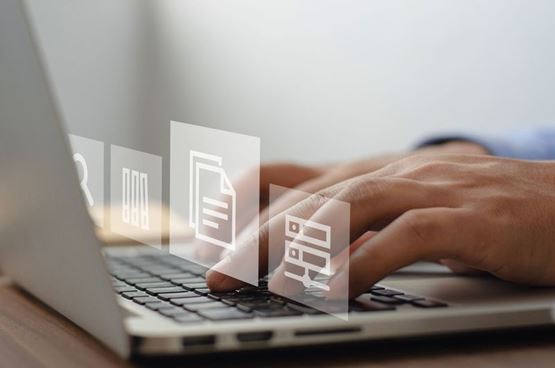 Gros plan sur une personne utilisant un ordinateur portable, avec des icônes numériques symbolisant la gestion de données, de documents et d’informations en ligne.